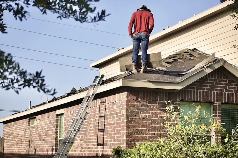 Professional roofer working on a residential roof in Adel